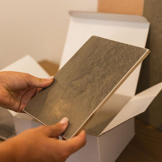 Person holding a sample of textured plaster material after pulling it out of a box